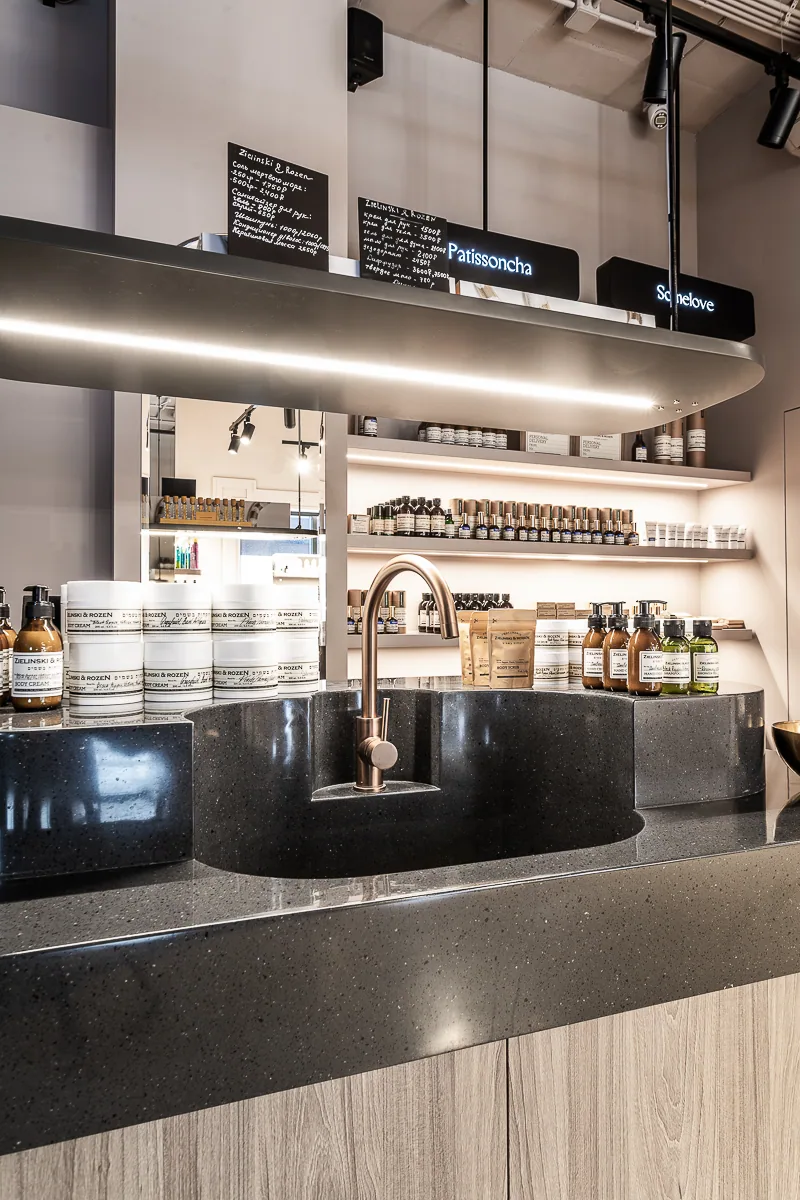Black stone perfume island with an integrated basin and illuminated shelving