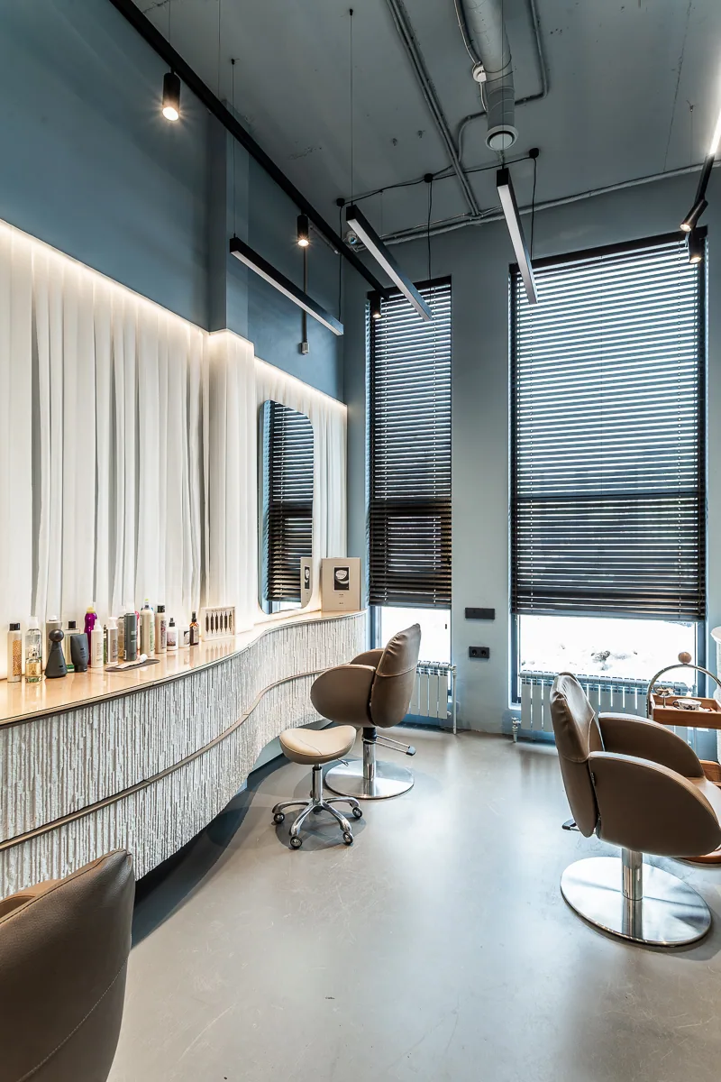 Hair studio with mirrors, curved worktops, and full-height daylight