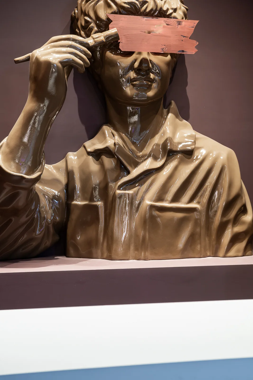 Close view of the classical figure painting a broad stroke across its face