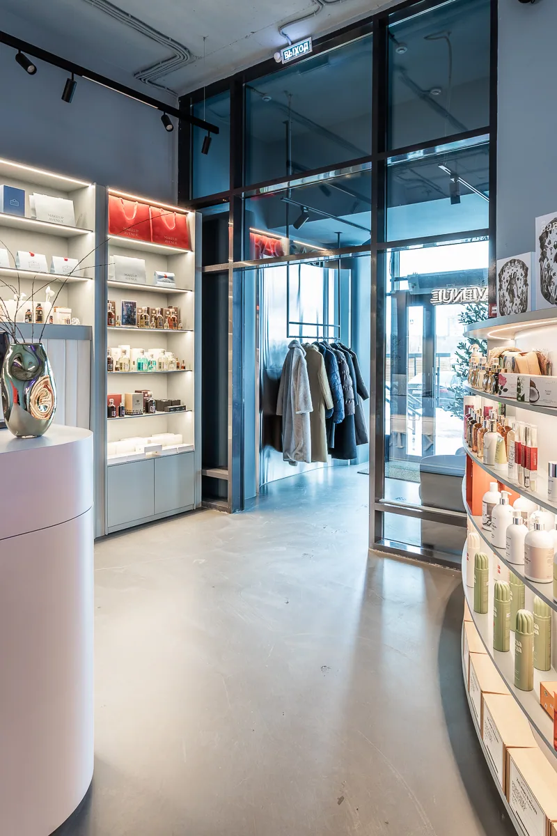 Boutique entrance with illuminated product shelving and a dark glazed portal