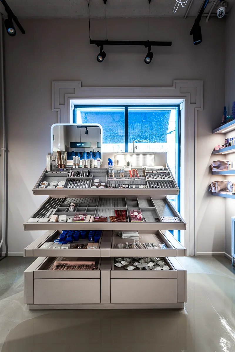 Tiered cosmetics display framed by a softly illuminated wall niche