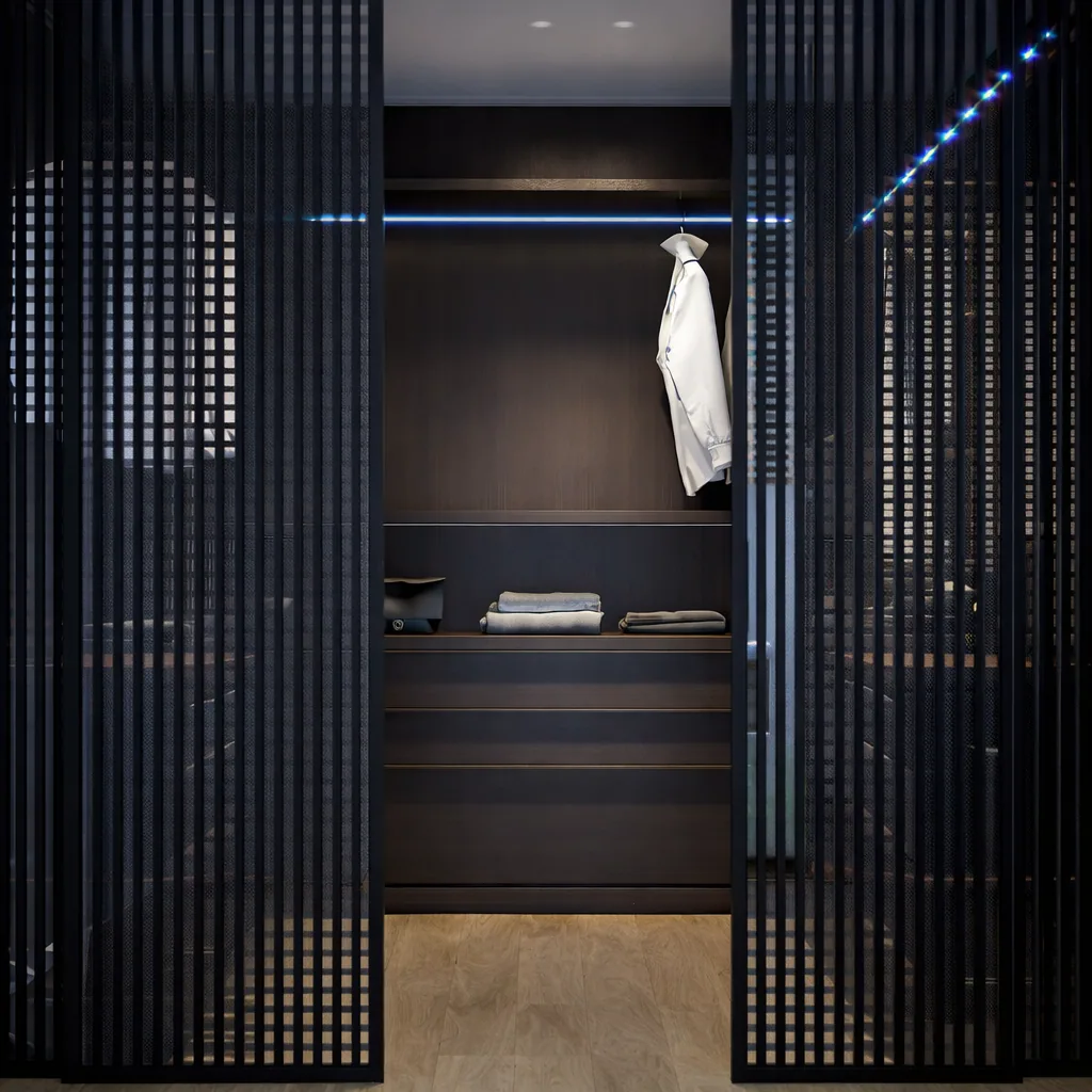 Walk-in wardrobe concealed behind black slatted sliding screens