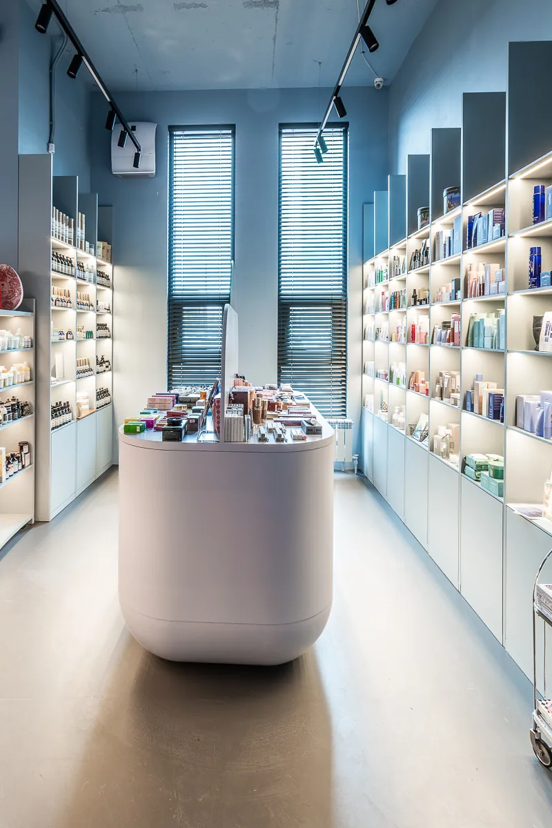 Central cosmetics island between two long walls of illuminated shelving