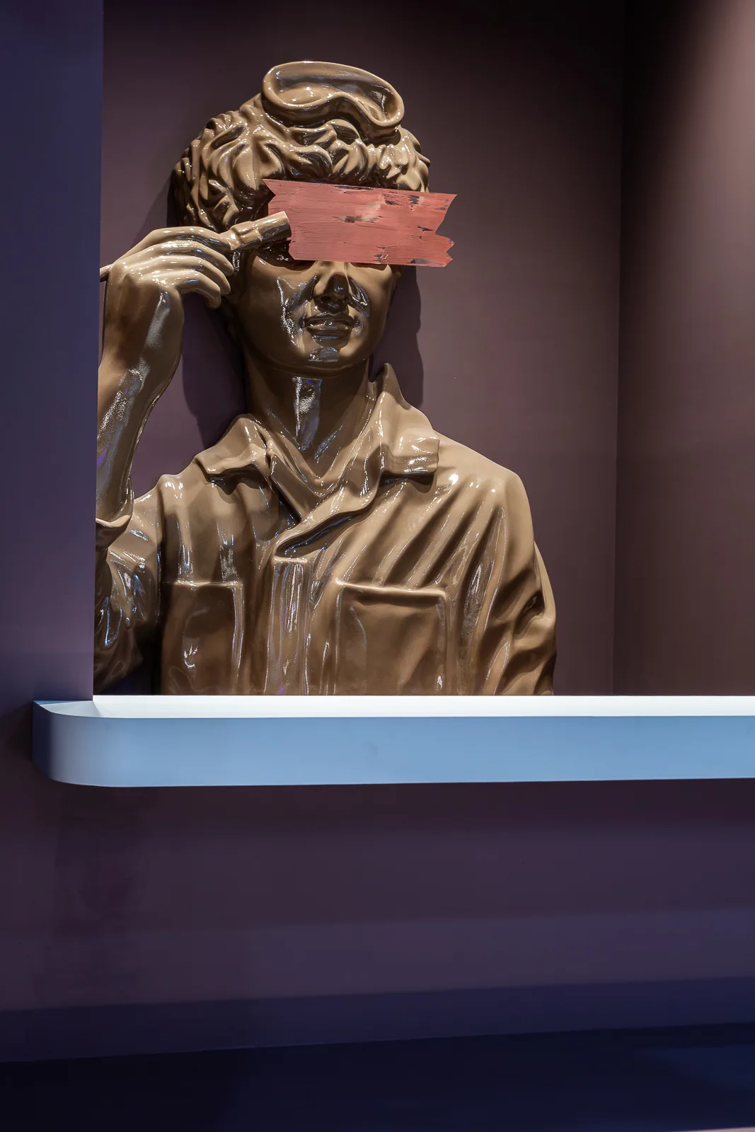 Classical sculptural figure marked by a broad painted stroke across the face